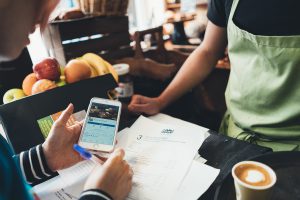 Woman holding iPhone filling in forms in coffee shop