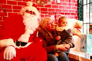 Traditional Father Christmas in Santa's Grotto with mother and child at Roman Road Winter Festival 2014